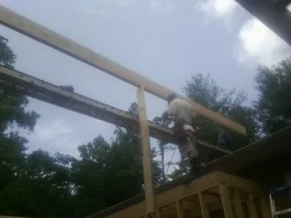 Carpenter setting a ridge beam over a new addition frame — Ice Dam Removal by Roofing Brothers in Lamoni