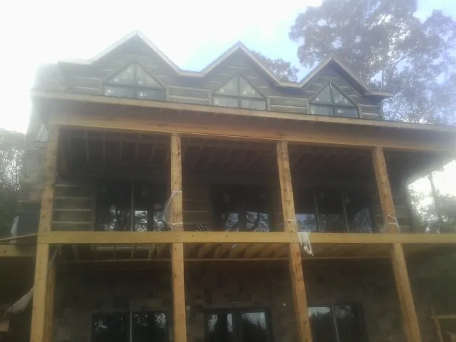 Dormers and porch framing on a large log home under construction — Roof Coating work by our crew in Lamoni
