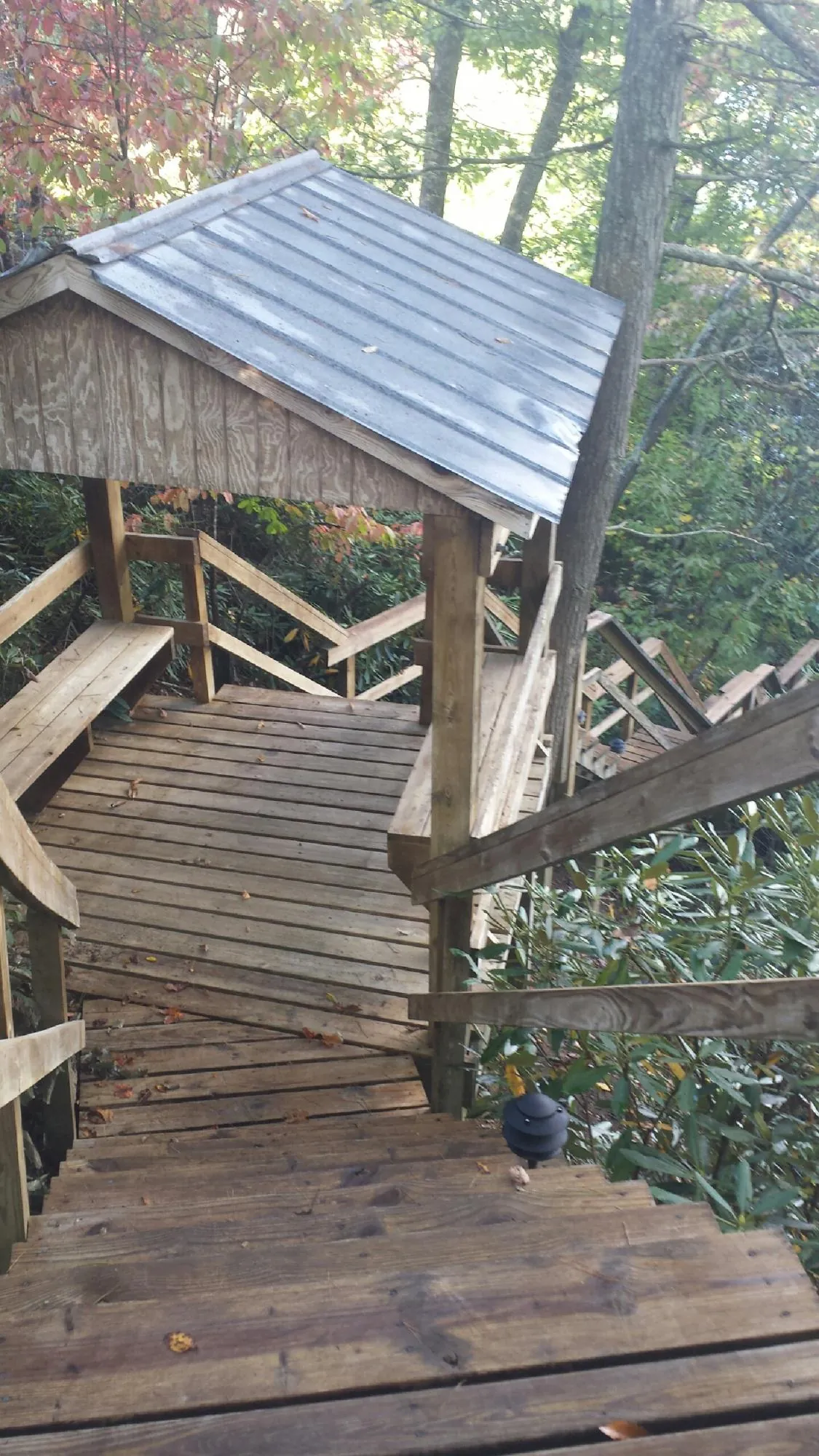 Metal roofed shelter over wooden steps on a wooded walkway — Skylight Repair & Installation work by our crew in Lamoni