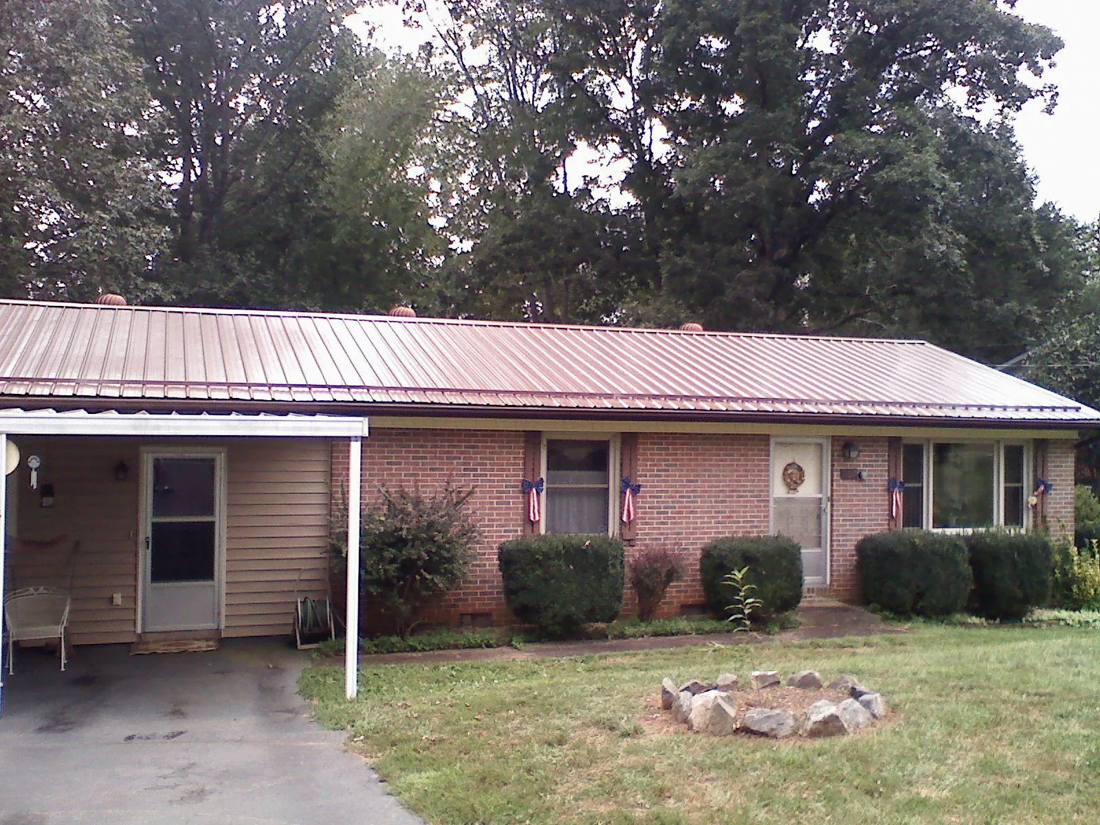 Bronze metal roof and carport on a brick ranch home — Roof Repair work by our crew in Lamoni
