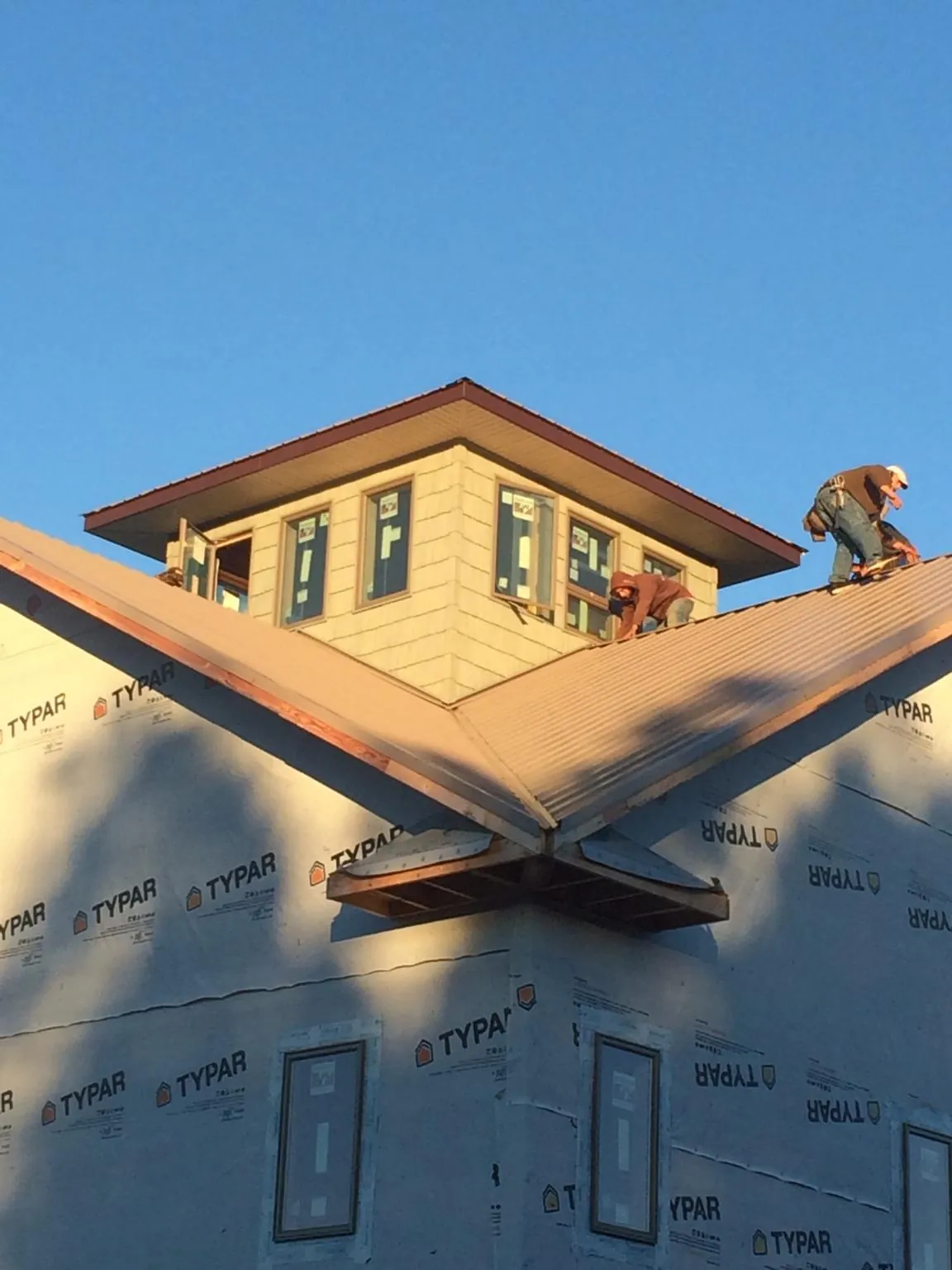 Roofers working around a rooftop cupola on a new metal roof at sunset — Roof Waterproofing in Lamoni by Roofing Brothers